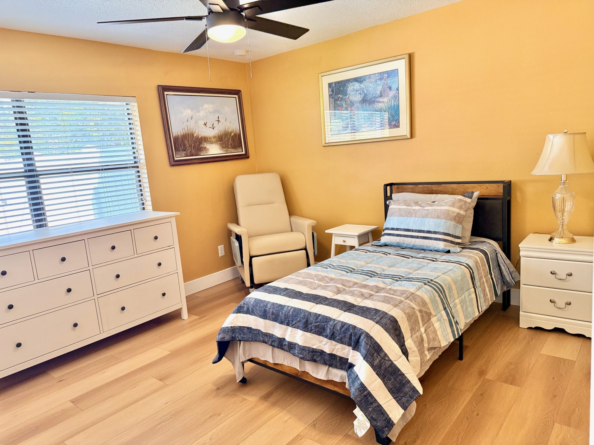 Private bedroom with single bed, personal dresser, recliner chair, and natural light at Lotus Home