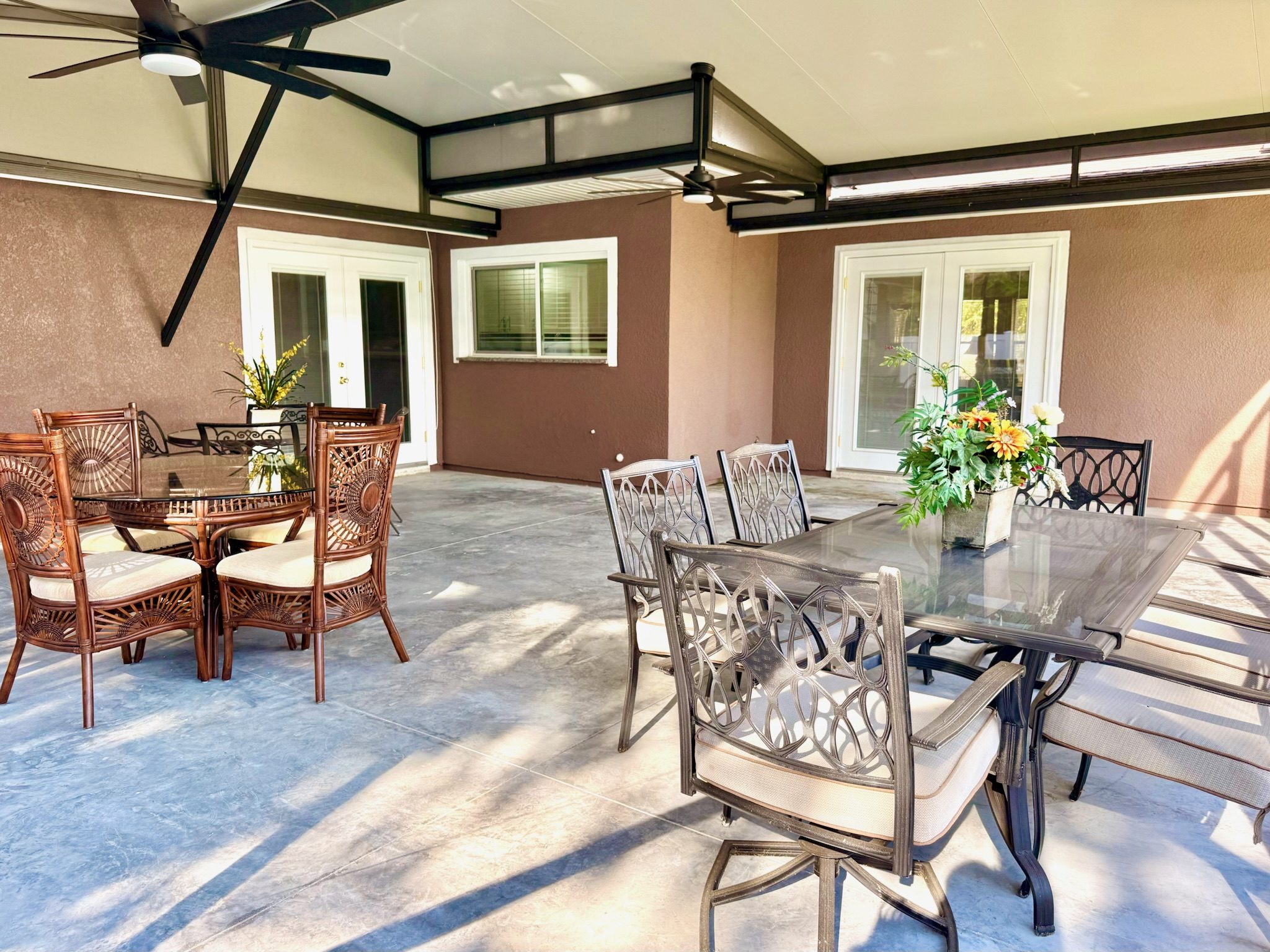 Spacious screened-in patio at Lotus Home with dining tables, ceiling fans, and lush garden views for outdoor relaxation